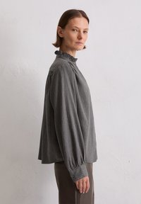Grijze gestreepte blouse met een geplooide hoge hals, lange mouwen met knoopmanchetten en een ontspannen pasvorm. Glad stof met subtiele textuur.