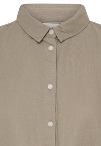 Chemise en lin beige avec un col classique pointu et quatre petits boutons blancs le long du plastron avant.