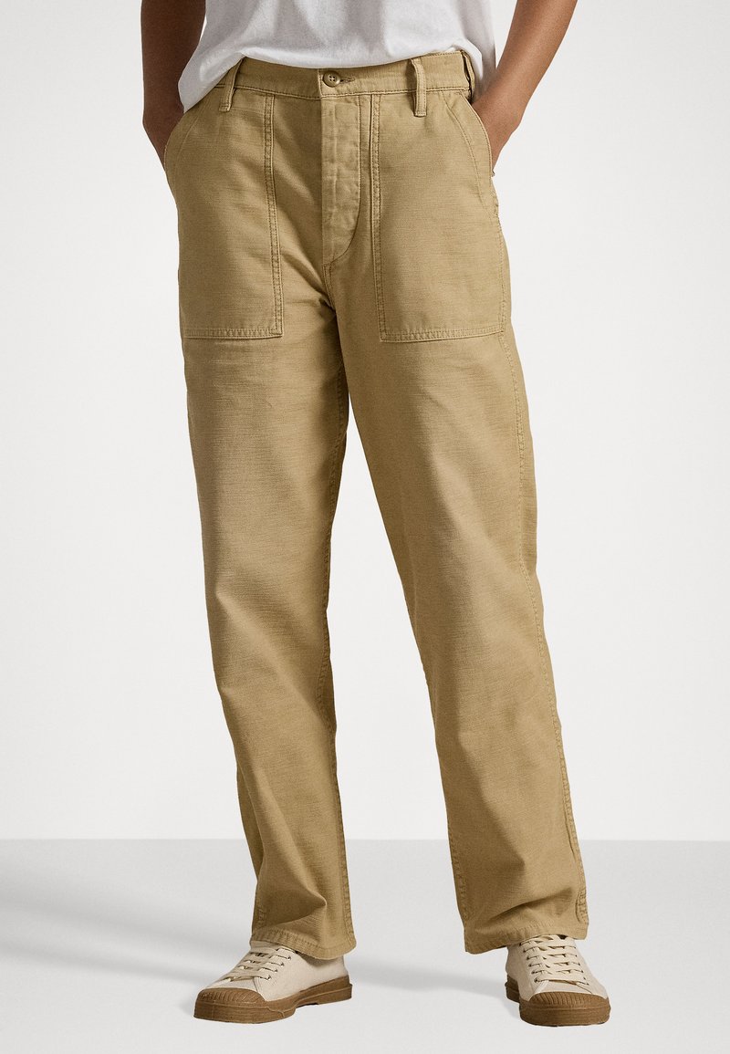 Canvasbyxor i ljusbeige, med rak benform, två framfickor, knappstängning och sömmar. Matchas med beige sneakers.