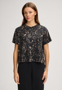 Svart kortärmad skjorta med djurmönster i beige och guld. Lös passform med rund halsringning och mjuk textur.