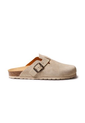 Beżowy zamszowy chodak z regulowanym paskiem na klamrę, profilowaną korkową wkładką oraz teksturowaną gumową podeszwą zapewniającą przyczepność i wygodę.