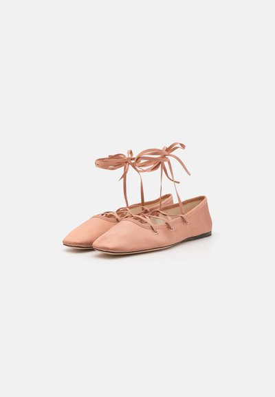 Bailarinas de color rosa claro, hechas de una tela suave, con puntera en punta y lazos en los tobillos, y una suela plana delgada.