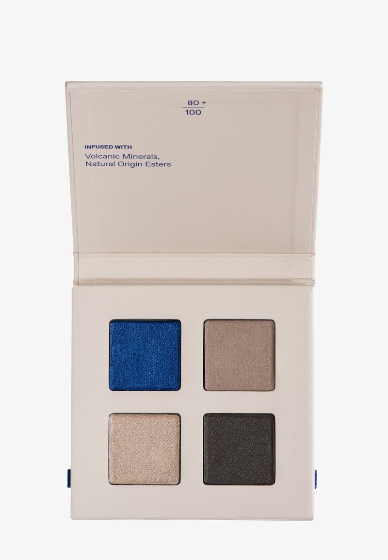 Palette de fards à paupières avec quatre teintes carrées : bleu métallique, taupe, beige clair irisé et gris charbon foncé dans un étui beige.