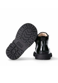 Stivali alla caviglia in pelle verniciata nera con una robusta suola in gomma nera caratterizzata da un motivo di battistrada. Texture liscia e design a punta rotonda.