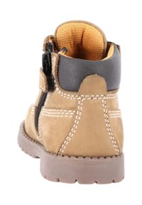 Stivaletto beige in pelle con colletto nero, zip laterale e cuciture bianche. Suola in gomma texture con motivo del battistrada pronunciato.