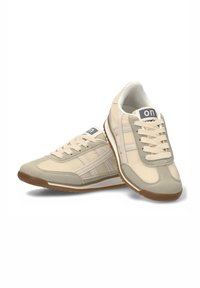 Zapatillas deportivas beige que presentan una combinación de materiales de gamuza y malla, punta redonda, diseño con cordones y una suela de goma de color contrastante.