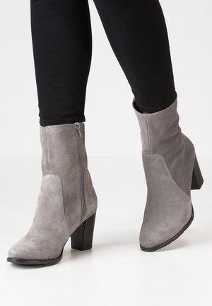 Bottes à talon bloc en suède gris avec une fermeture éclair sur le côté et un design à bout pointu. Matériau texturé et lignes épurées.
