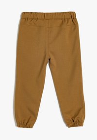 Brune bomuldsbukser med elastisk talje og elastiske manchetter ved anklerne. Stoffet har en glat tekstur og et enkelt design.