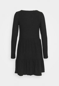 Robe noire à manches longues avec texture côtelée, corsage ajusté et jupe évasée. Elle possède un col rond et un ourlet en couches.