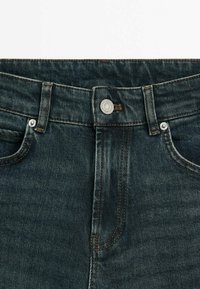 Dark blue denim jeans with a high waistband, featuring a metal button, contrasting stitching, and classic five-pocket design.