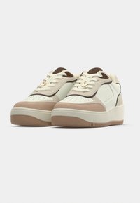 Λευκά και καφέ δερμάτινα αθλητικά παπούτσια  με σόλα πλατφόρμας, με διάτρητα διακοσμητικά στοιχεία, κορδόνια και μια μικρή χρυσή μεταλλική λεπτομέρεια.