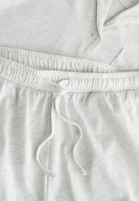 Ensemble de pyjama gris clair avec un haut à col boutonné et un pantalon à taille élastique présentant un cordon à nouer à l'avant.