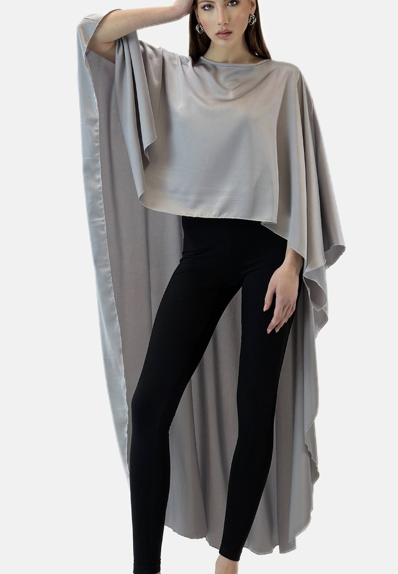 Grå satin-cape topp med vida ärmar, lager-på-lager design och en flödande silhuett, kombinerad med svarta figursydda leggings. Mjuk textur.