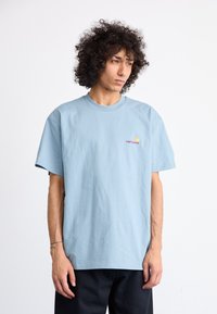 Light blue cotton t-shirt with a crew neck, short sleeves, and a small embroidered logo on the chest. Simple, relaxed fit.