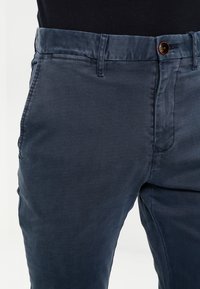 Slim-fit marina blå chinos i bomullsmixmaterial, med en slät textur, knappstängning och sidofickor.