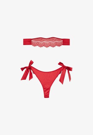 Rotes Spitzen-Bandeau-Top und passender Satin-Bikini-Slip mit seitlichen Schleifen, flach auf weißem Hintergrund ausgelegt.
