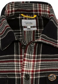 Camisa de franela a cuadros en negro, rojo y gris. Cuenta con un cuello abotonado, bolsillo en el pecho y un parche con logo. Ajuste relajado, fabricada en una mezcla de algodón.
