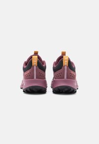 burgundy and black sneakers with a textured finish, orange pull tab, and a rugged sole, featuring padded ankle support and ventilation holes.