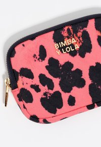 Rožinė audinio kišenė su juodu leopardų raštu, auksinėmis detalių ir užtrauktuko uždarymu. Priekyje yra įspaustas "BIMBA Y LOLA" logotipas.