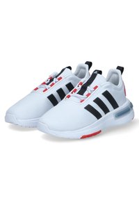Baskets de sport blanches avec une tige en mesh, des accents noirs et trois rayures noires. Présente un insert au talon rouge et un amorti d'air visible.