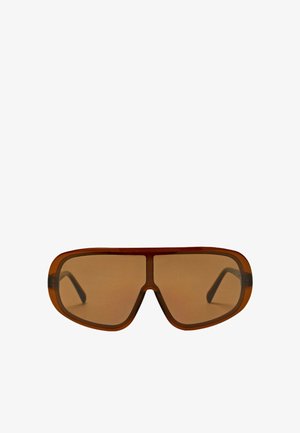 Lunettes de soleil surdimensionnées style bouclier marron avec une monture épaisse et des verres teintés sur fond blanc.