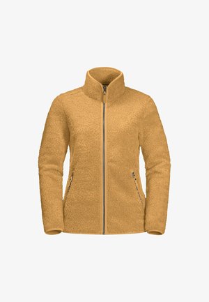 Personne portant une veste polaire beige zippée intégralement, mains dans les poches avant zippées, assortie à un pantalon gris.