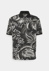 Czarny i biały polo z misternymi wzorami paisley i lamparta, z krótkimi rękawami i czarnym kołnierzykiem. Tkanina wydaje się miękka i teksturowana.