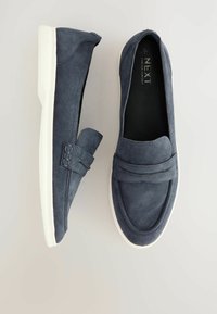 Navy suede slip-on shoes with a smooth texture, featuring a decorative strap and white rubber sole. Minimalist design with no visible patterns.