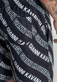 Crne kratke hlače s ponavljajućim uzorkom bijelog logotipa. Elastični pojas i bočna džep su istaknuti detalji. Glatka, lagana tkanina.