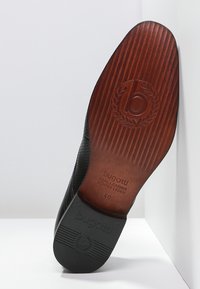 Semelle de chaussure en cuir noir avec un motif texturé, présentant une finition en bois et un logo embossé. Taille 40 et marqué "cuir véritable".
