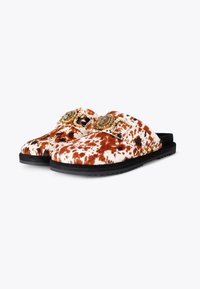Cow print slide slippers in brown and white faux fur, featuring gold-tone hardware accents and a black rubber sole. Textured surface.