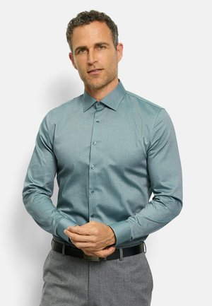 Turquoise long-sleeve shirt with a subtle pattern, button-up design, and collared neckline. Paired with gray pants and a black belt.
