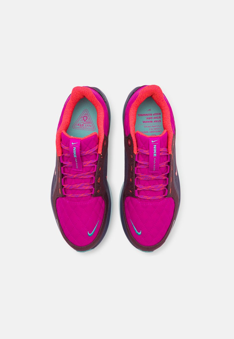 Lila und pinke Sportschuhe mit einem gesteppte Design, strukturiertem Stoff, kontrastierender leuchtend orangefarbener Innenausstattung und einem türkisfarbenen Logo.