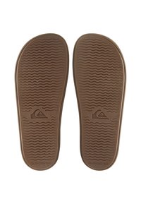 Brune gummiflip-flopsåler med et teksturert bølge-mønster, som har Quiksilver-logoen preget på hver såle nær hælen.