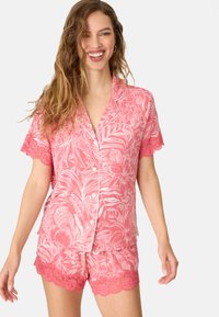 Roze pyjama set met bloempatronen, korte mouwen en gerafelde kantaccenten. Gemaakt van zachte stof, met knopen en een ontspannen pasvorm.