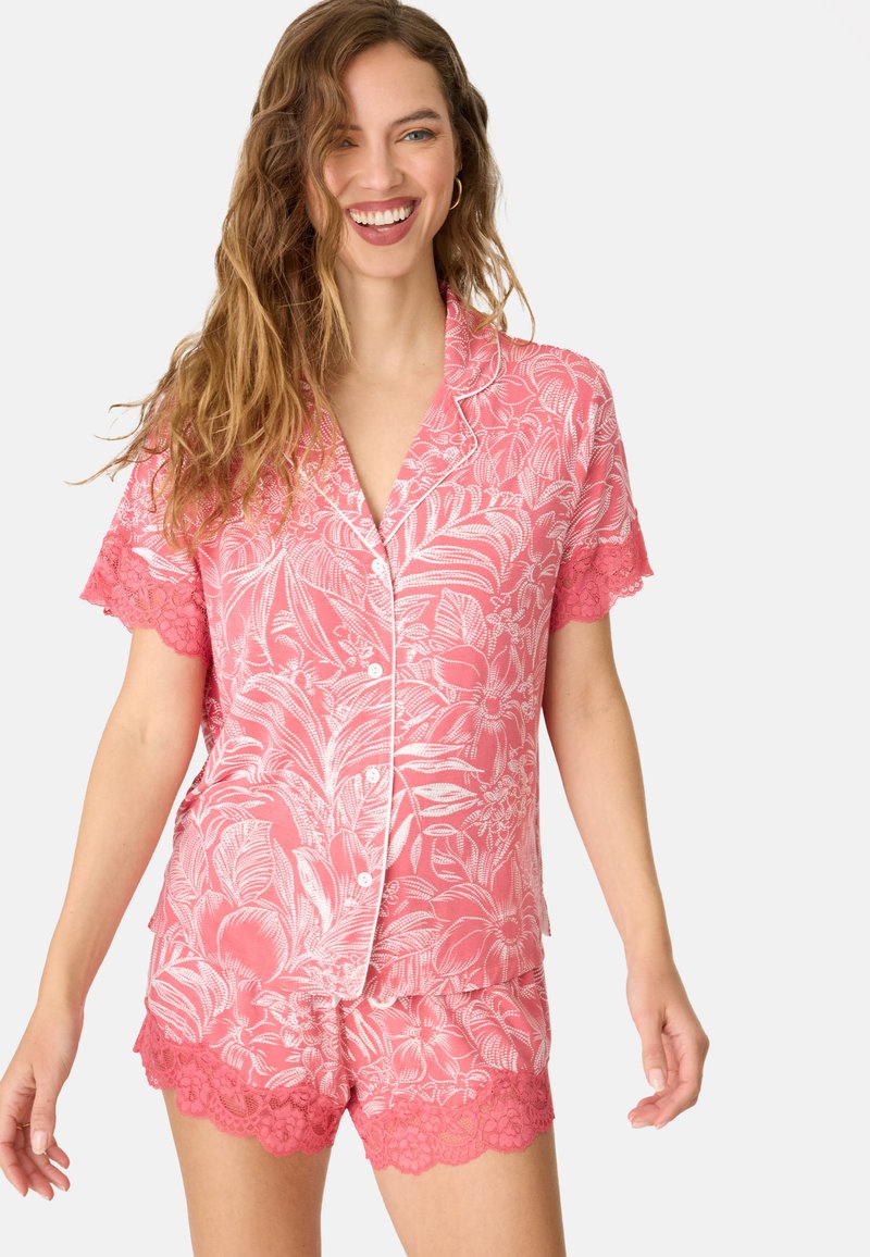 Roze pyjama set met bloempatronen, korte mouwen en gerafelde kantaccenten. Gemaakt van zachte stof, met knopen en een ontspannen pasvorm.