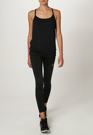 Czarny sportowy top na ramiączkach z cienkimi paskami i luźnym krojem, zestawiony z czarnymi dopasowanymi legginsami z dyskretnym logo oraz czarnymi butami do biegania.