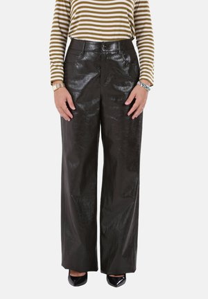 Pantaloni neri a gamba larga realizzati in materiale lucido e strutturato, con vita alta e tasche frontali. Abbinati a una maglia a righe e tacchi.