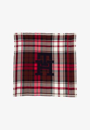 Coperta a scacchi con tonalità di rosso, marrone, grigio e bianco. Presenta un logo scuro al centro e un tessuto morbido e dalla texture piacevole.