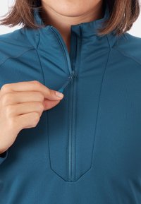 Niebieski pół-zamek polarowy wykonany z gładkiego, rozciągliwego materiału, z podwyższonym kołnierzem i zamkiem błyskawicznym z małym uchwytem.