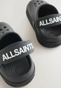 Zwarte rubberen klompen met ventilatiegaten, dikke witte band met "ALLSAINTS" tekst, gemodelleerde voetbed en afgeronde vorm.