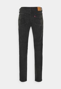 Svart denim skinny jeans med texturerad finish, fem fickor, bältesslingor och en läderlapp vid bakre midjan.