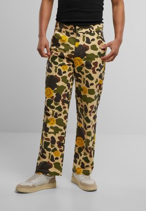 Camo-mønstret bukser i khaki med gule smiley-face grafikker. Lige ben-design med lommer og knaplukning.