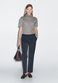 Grijze korte mouwen coltrui, marineblauwe op maat gemaakte broek, bruin leren handtas en loafers. Glad textuur, minimalistisch ontwerp, getailleerde silhouet.