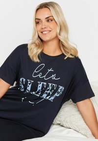 Marinblå kortärmad sovskjorta med texten "Låt oss sova" i ljusblå leopardmönstrad skrift på framsidan. Mjuk tyg, avslappnad passform.