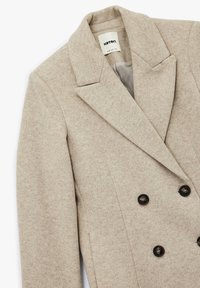 Beige Wolle-Mischung Blazer, doppelt geknopftes Design, mit Reverskragen und zwei schwarzen Knöpfen. Strukturierter Stoff mit glatter Innenseite.
