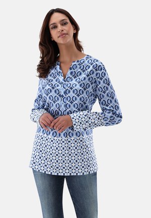 Blue patterned shirt featuring circular and geometric designs. Long sleeves with contrasting cuffs. Button-up collar and loose fit.