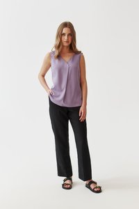 Lilac ilmanhiha blouse, jossa on V-päivä ja pehmeä laskos, yhdistettynä mustiin suoriin housuihin ja mustiin sandaaleihin, joissa on kultaisia yksityiskohtia.