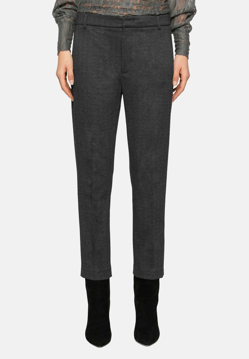 Pantalon sur mesure gris foncé avec un motif pied-de-poule subtil, coupe slim, passants de ceinture et texture lisse, associé à des bottes noires à talons.