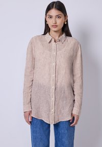 Camicia con colletto a maniche lunghe in un tessuto beige chiaro con sottili righe verticali e bottoni nella parte anteriore. Vestibilità morbida con maniche a polsino.